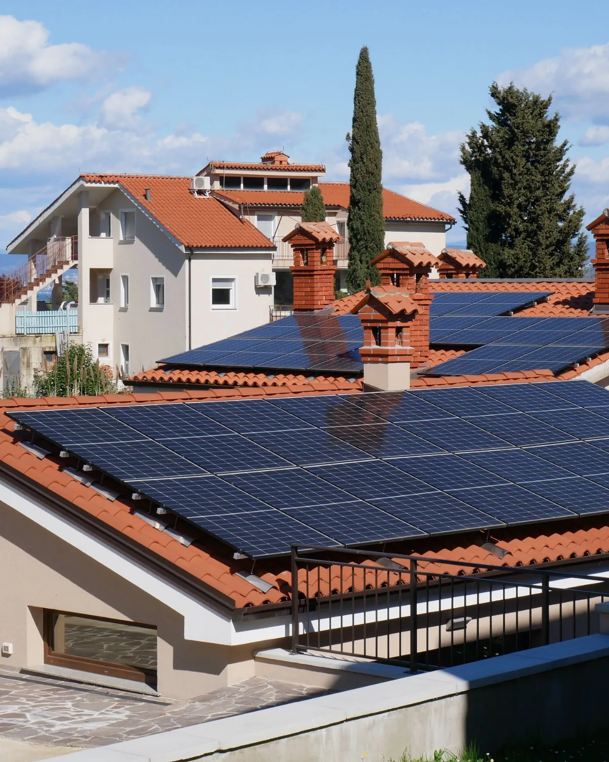 Chalet de tejados rojos con placas solares negras en el tejado, bajo un cielo azul